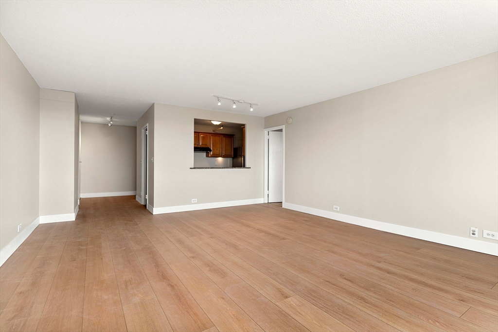 151 Tremont Street, Unit 23P Boston, MA 02111 - Photo 6 of 35 a view of an empty room with wooden floor and a window