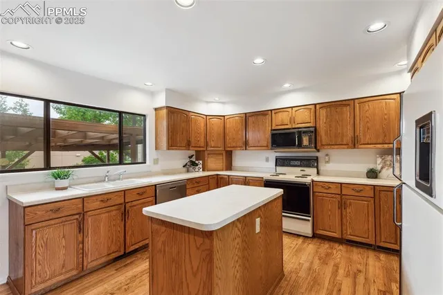 a kitchen with a sink a counter top space stainless steel appliances a large window and cabinets