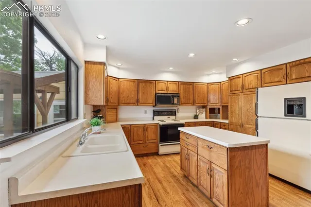 a large kitchen with stainless steel appliances a stove a refrigerator a sink dishwasher with a dining table and chairs with wooden floor