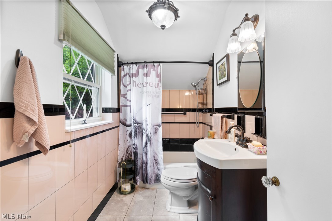 443 Merriman Road Akron, OH 44303 - Photo 25 of 44 Bathroom featuring pink ceramic wall tiling with black accent bands, a diamond-pane window, and a dark wood-finish vanity with an integrated sink