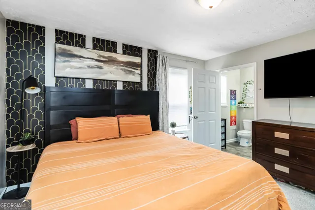 a bedroom with a bed and a flat tv screen on wall