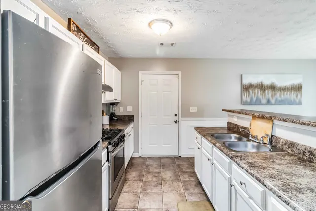 a kitchen with granite countertop a refrigerator stove and sink