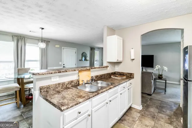 a kitchen with a stove a sink a refrigerator and chairs