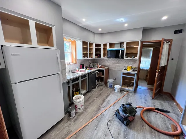 a kitchen with stainless steel appliances granite countertop a refrigerator a stove a sink dishwasher and a refrigerator with wooden floor