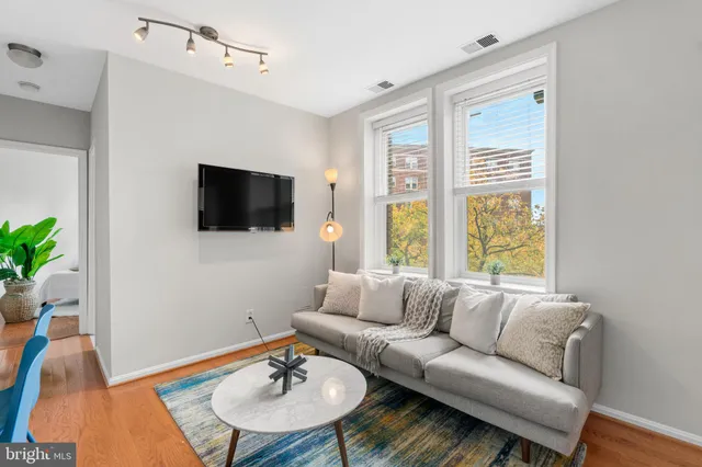 a living room with furniture a flat screen tv and a window