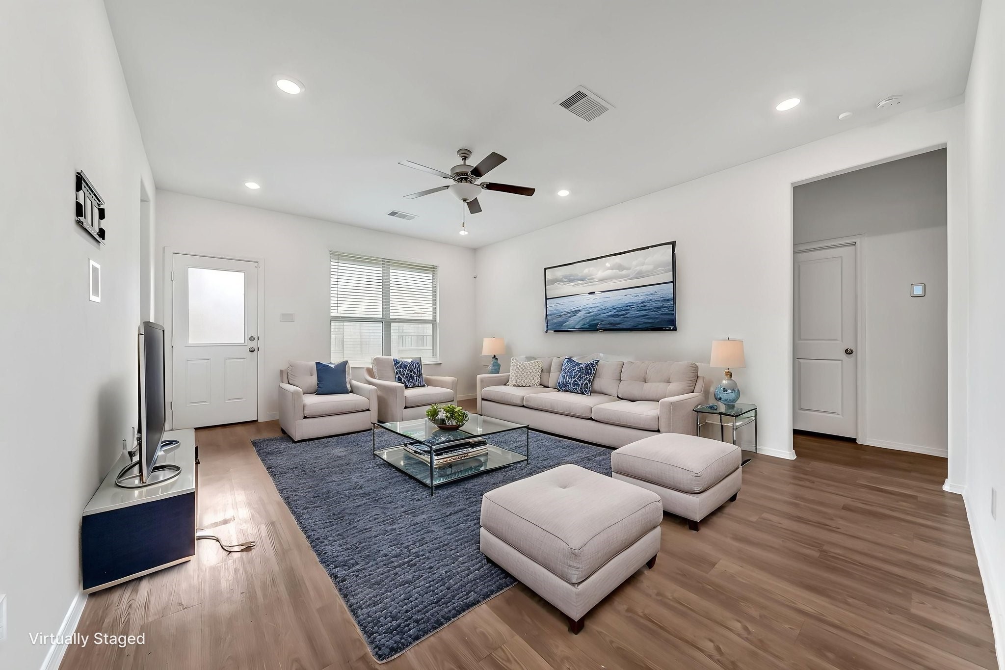2847 Mistygate Court Conroe, TX 77301 - Photo 3 of 27 This virtually staged living room features a modern, open design with neutral tones, wood flooring, and ample natural light. It includes a comfortable seating area, a large wall-mounted TV, and elegant decor.