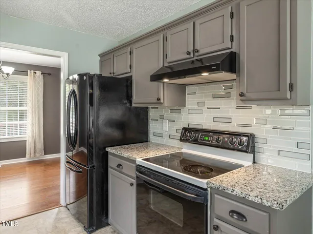 a kitchen with granite countertop a stove sink and refrigerator