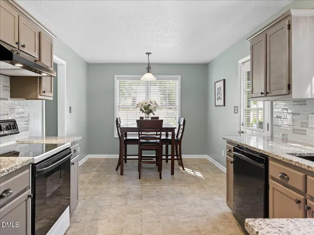 a kitchen with stainless steel appliances granite countertop a stove top oven a sink dishwasher a dining table and chairs with wooden floor