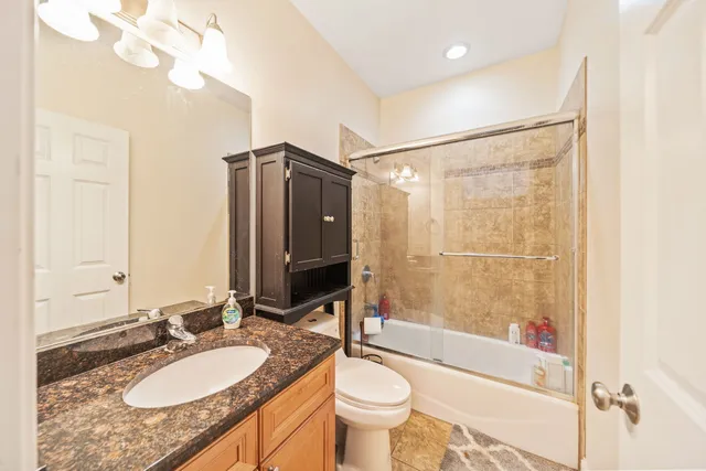 a bathroom with a granite countertop sink toilet mirror and shower