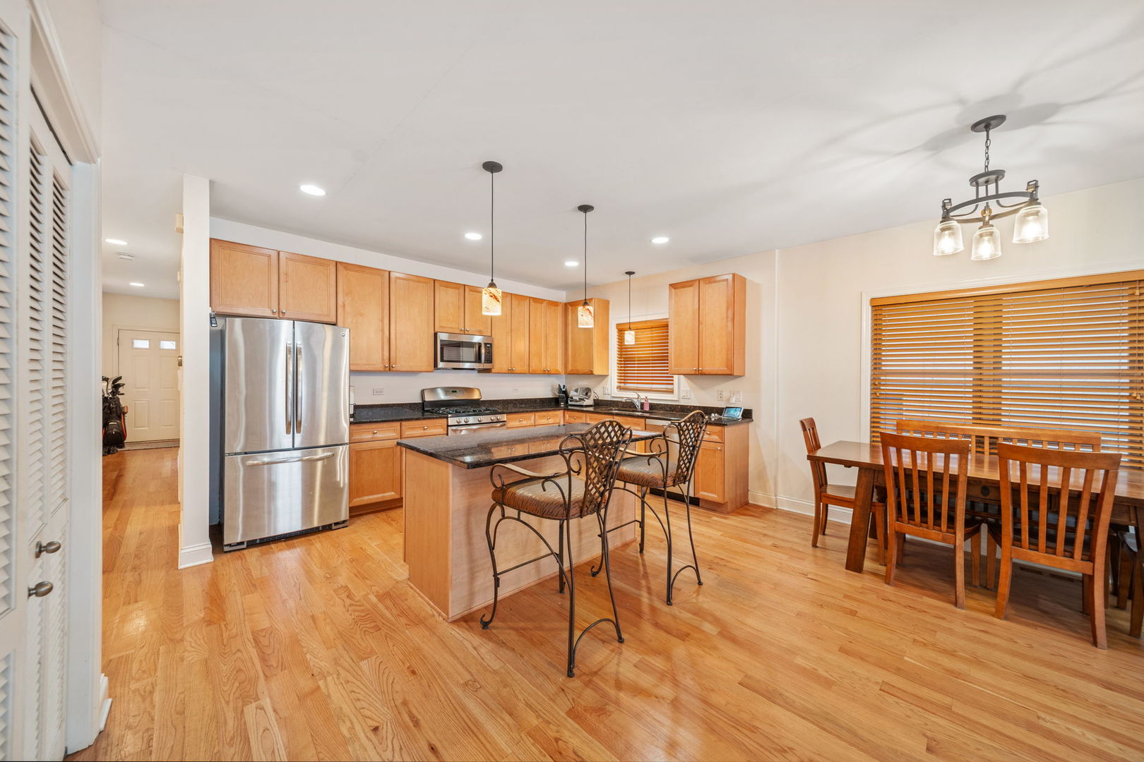 3213 South Wells Street, Unit 1 Chicago, IL 60616 - Photo 3 of 28 a kitchen with stainless steel appliances kitchen island granite countertop a refrigerator a stove a sink a dining table and chairs with wooden floor