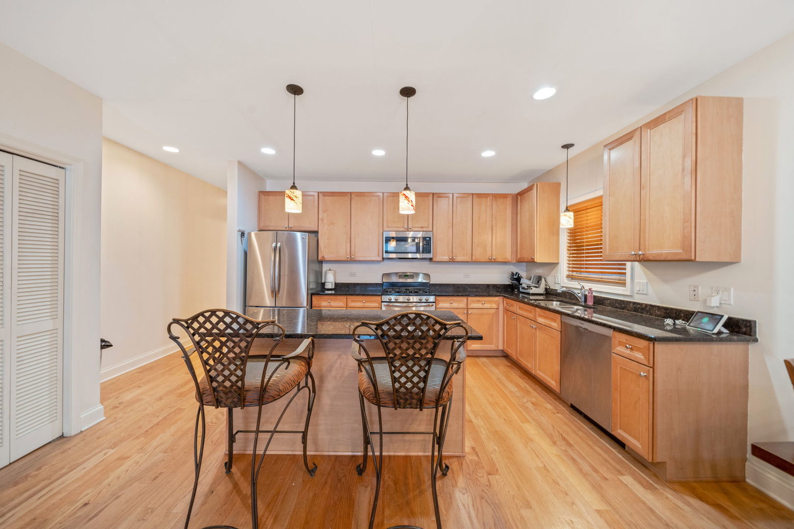 3213 South Wells Street, Unit 1 Chicago, IL 60616 - Photo 4 of 28 a kitchen with stainless steel appliances granite countertop a kitchen island a stove a sink a refrigerator with a dining table and chairs