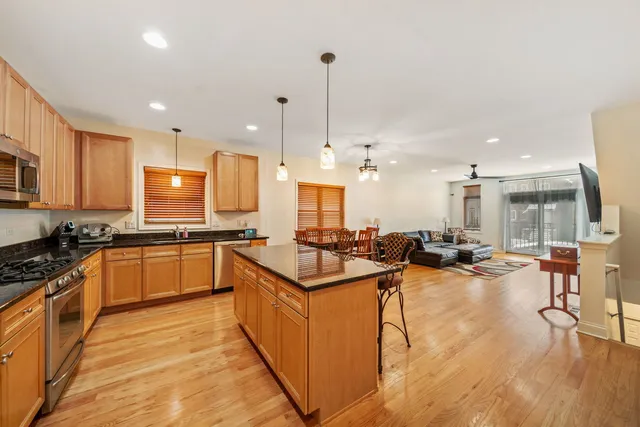a kitchen with stainless steel appliances kitchen island granite countertop a stove a sink a refrigerator and chairs