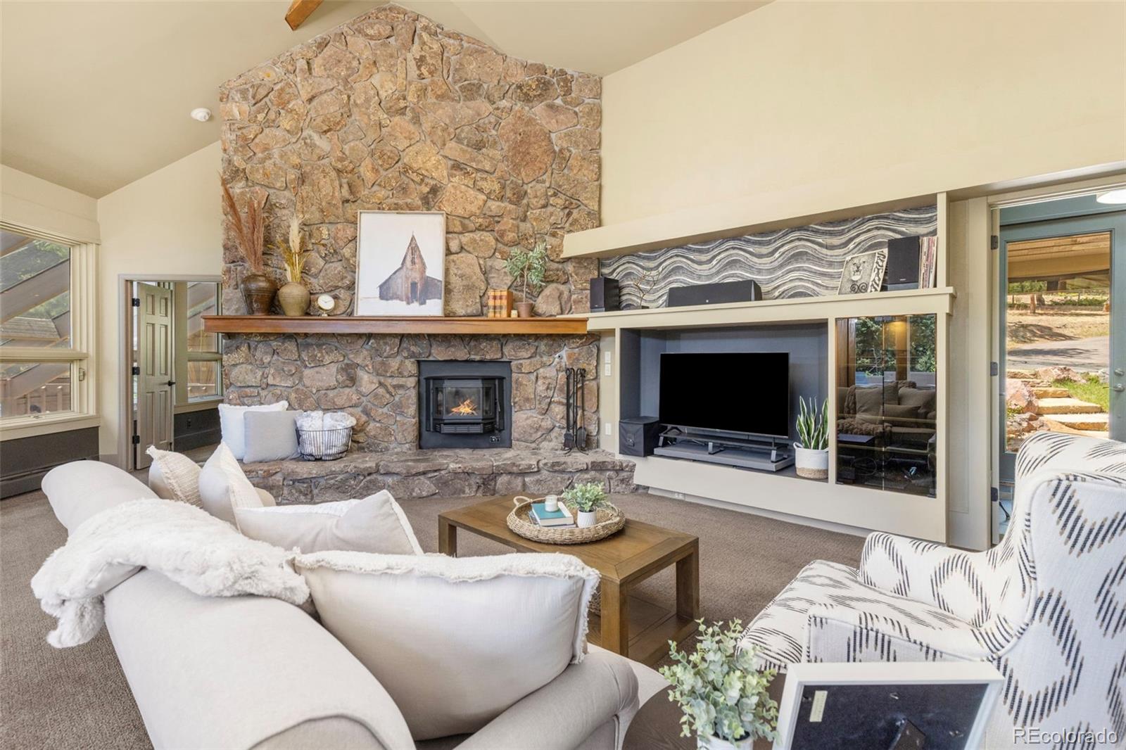 1323 South Snyder Gulch Road Evergreen, CO 80439 - Photo 5 of 47 a living room with furniture a flat screen tv and a fireplace