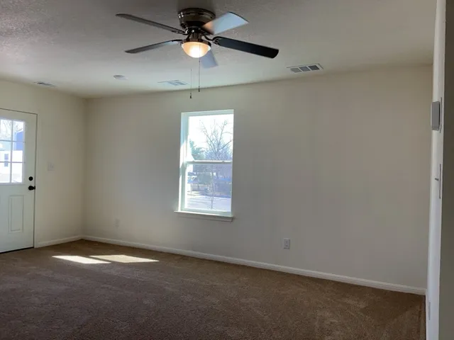 an empty room with a window and a fan