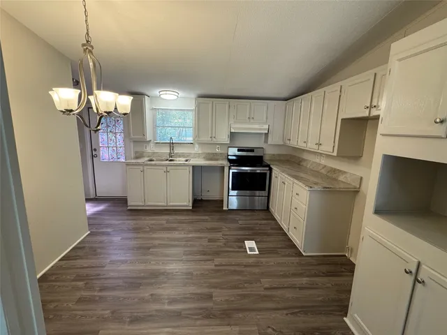 a kitchen with kitchen island granite countertop wooden floors stainless steel appliances a sink and a stove