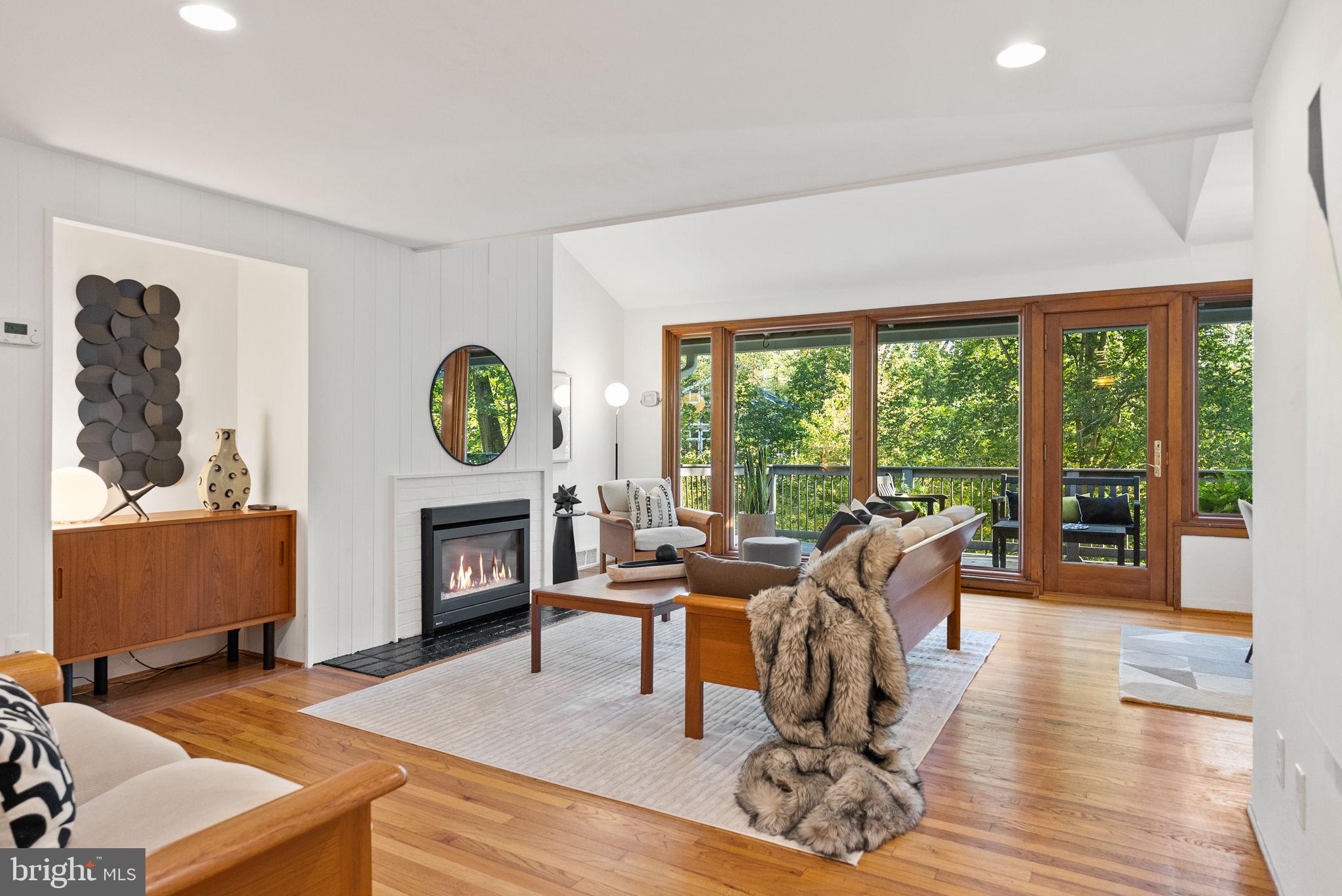 7111 Braeburn Place Bethesda, MD 20817 - Photo 7 of 86 a living room with furniture a fireplace a large window and a wooden floor