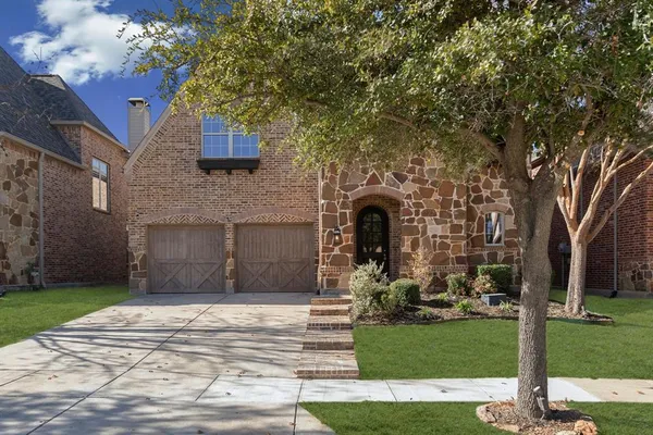 a front view of a house with a garden and tree