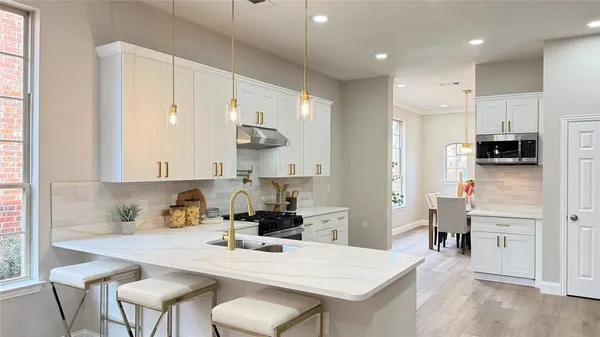 a large kitchen with stainless steel appliances granite countertop a stove and white cabinets
