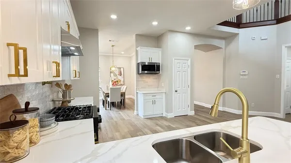 a kitchen with stainless steel appliances granite countertop white cabinets granite counter tops and a hard wood floors