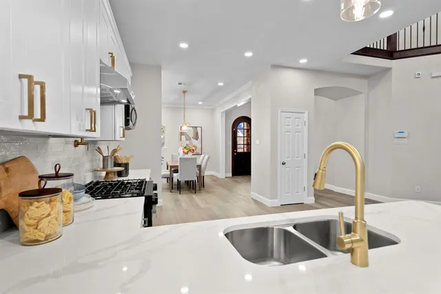 a kitchen with kitchen island a dining table chairs sink and cabinets