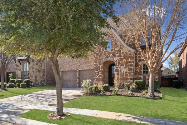 a front view of a house with a garden and trees