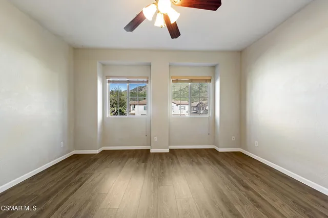 an empty room with wooden floor exposed radiator and windows