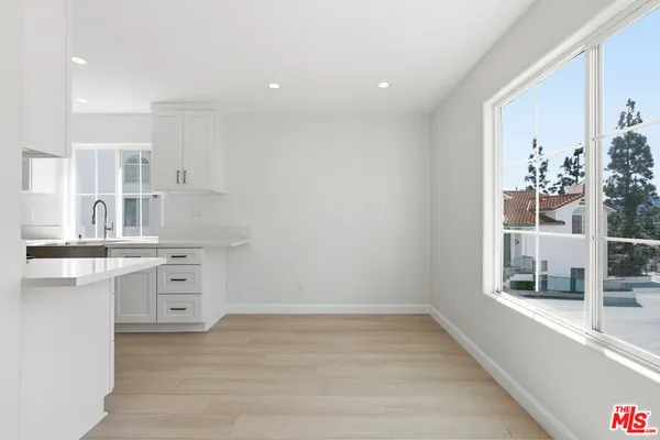 an empty room with a kitchen island a sink wooden floor and a large window