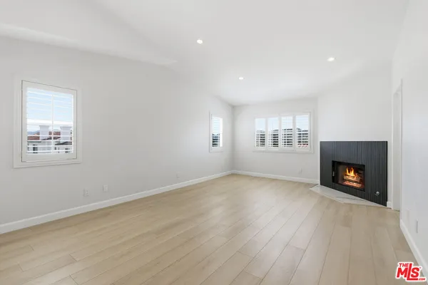 a view of an empty room with wooden floor fireplace and a window