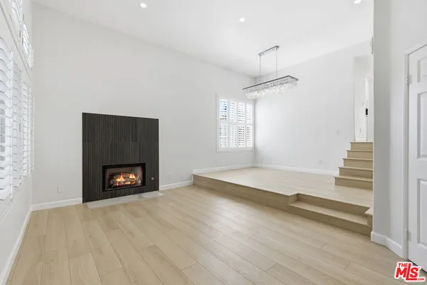 an empty room with windows and fireplace