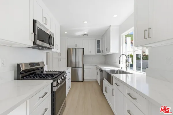 a kitchen with stainless steel appliances a refrigerator a sink a stove top oven a sink and cabinets