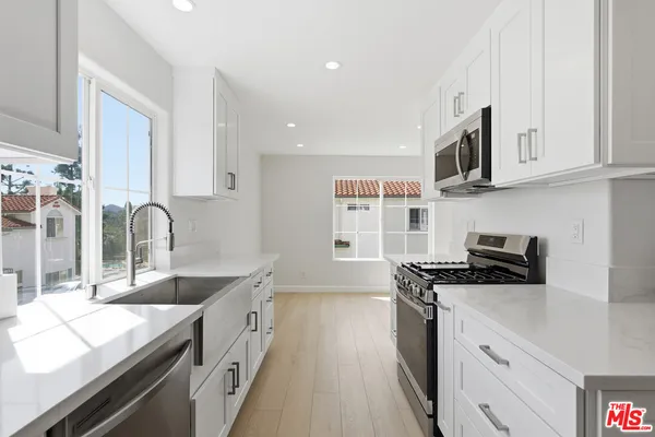 a kitchen with stainless steel appliances granite countertop a stove a sink and a microwave