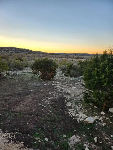 a view of a dry yard with mountains in the background