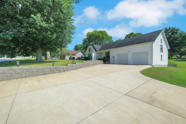 a view of a house with a yard and large trees
