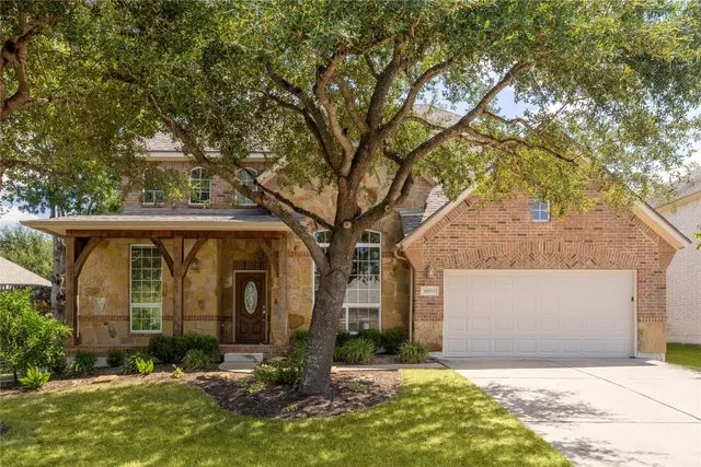 a view of house with yard and a large tree