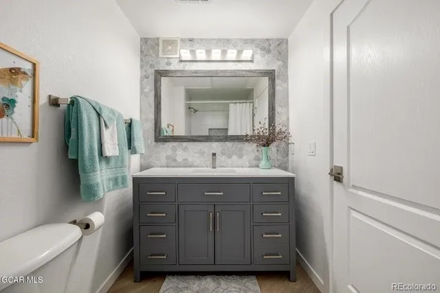 a bathroom with a granite countertop sink a toilet and a mirror