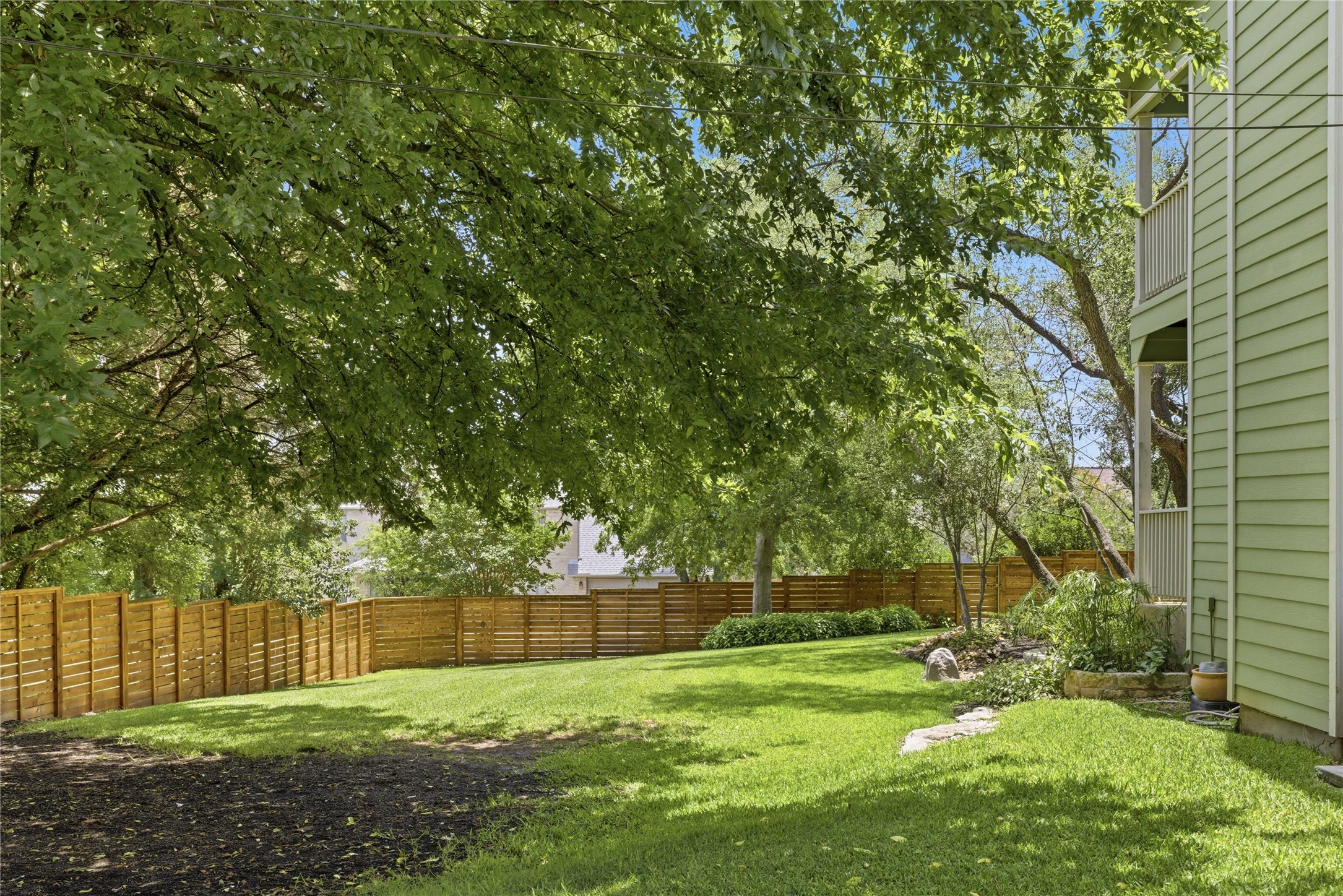 1204 Orlando Road Austin, TX 78733 - Photo 21 of 40 A verdant backyard with mature shade trees, a well-maintained lawn, and privacy fencing.