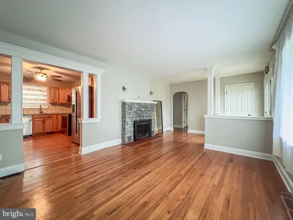 an empty room with wooden floor fireplace and windows