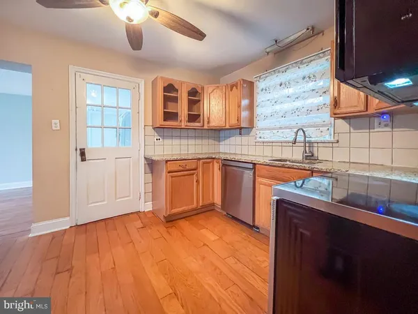 a kitchen with stainless steel appliances granite countertop a sink dishwasher and wooden cabinets with wooden floor
