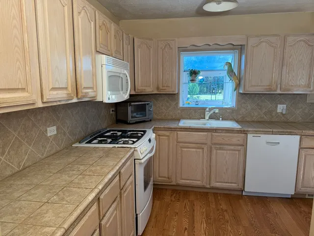 a kitchen with granite countertop cabinets stainless steel appliances a sink and wooden floor