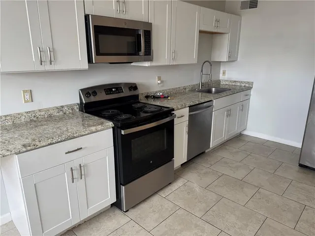 a kitchen with cabinets appliances a sink and a counter top space