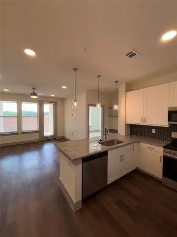 a large kitchen with stainless steel appliances a large counter top a stove a sink dishwasher and a oven with white cabinets