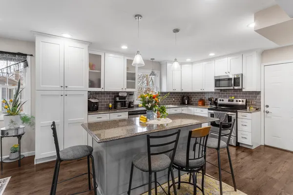 a kitchen with a dining table chairs wooden floor appliances and cabinets