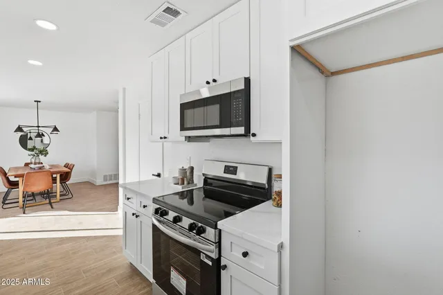 a kitchen with a sink dishwasher and white cabinets with wooden floor