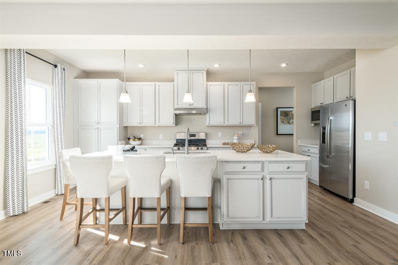 548 Impala Trace Wendell, NC 27591 - Photo 3 of 10 a kitchen with stainless steel appliances cabinets a dining table and chairs