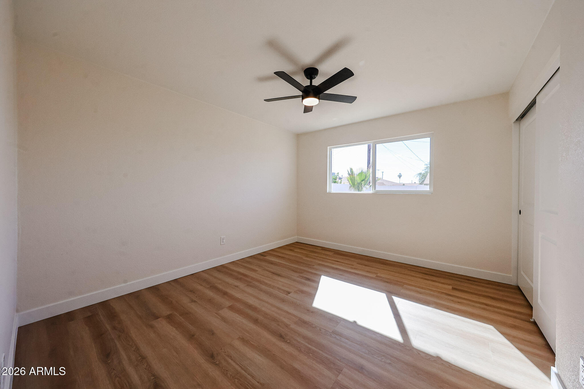3337 West Ocotillo Road Phoenix, AZ 85017 - Photo 18 of 30 an empty room with wooden floor a ceiling fan and windows