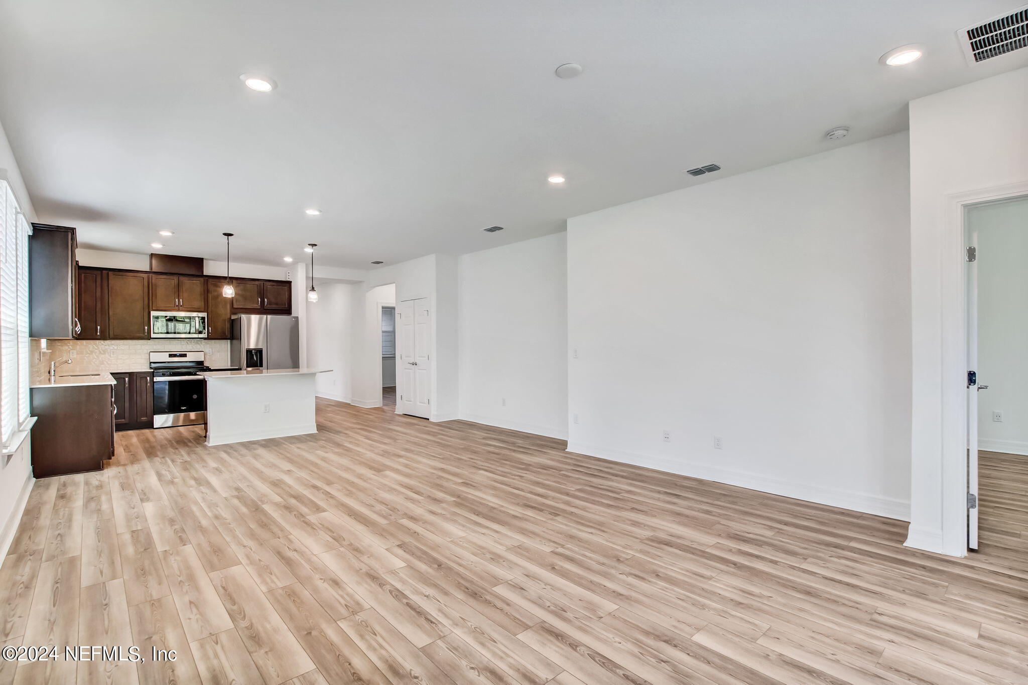 524 Jubilee Circle Yulee, FL 32097 - Photo 8 of 25 a view of kitchen with microwave a refrigerator and a stove top oven with wooden floor
