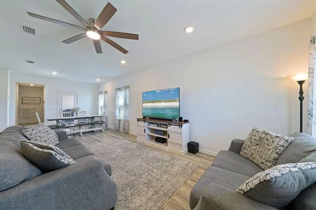 a living room with furniture a flat screen tv and a wooden floor