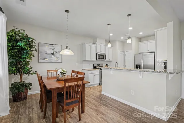 a kitchen with stainless steel appliances kitchen island a table and chairs in it