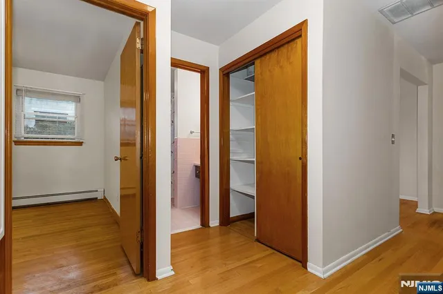 a view of a hallway with wooden floor and a bathroom
