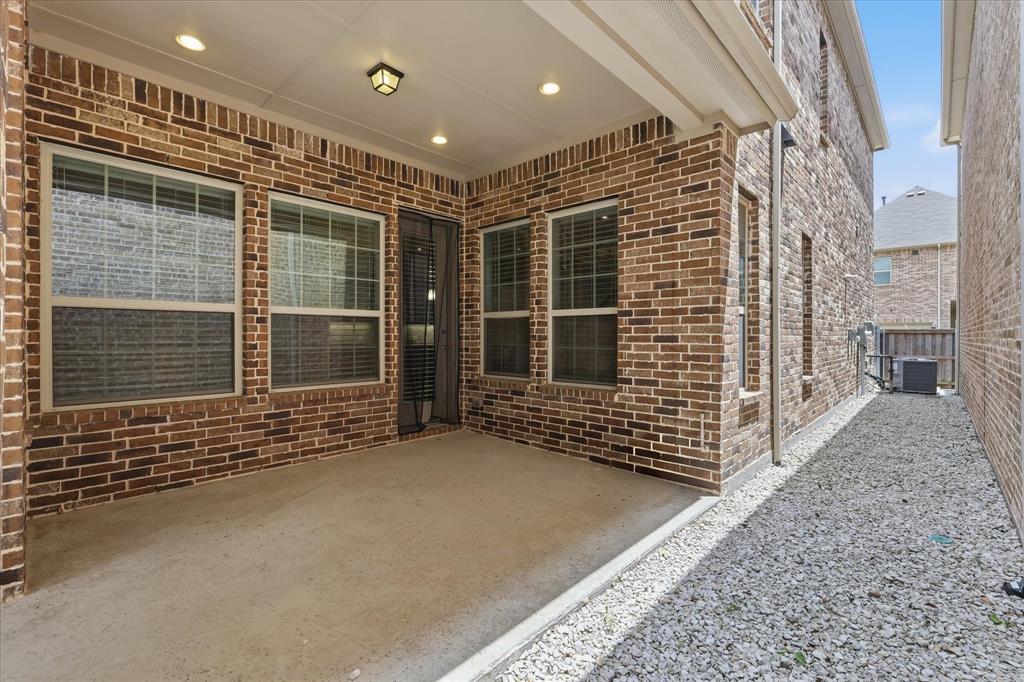 768 Huntingdon Street Coppell, TX 75019 - Photo 35 of 37 Covered rear patio with recessed lighting, brick surround, and multiple windows overlooking the outdoor space — a comfortable spot for morning coffee or evening relaxation.